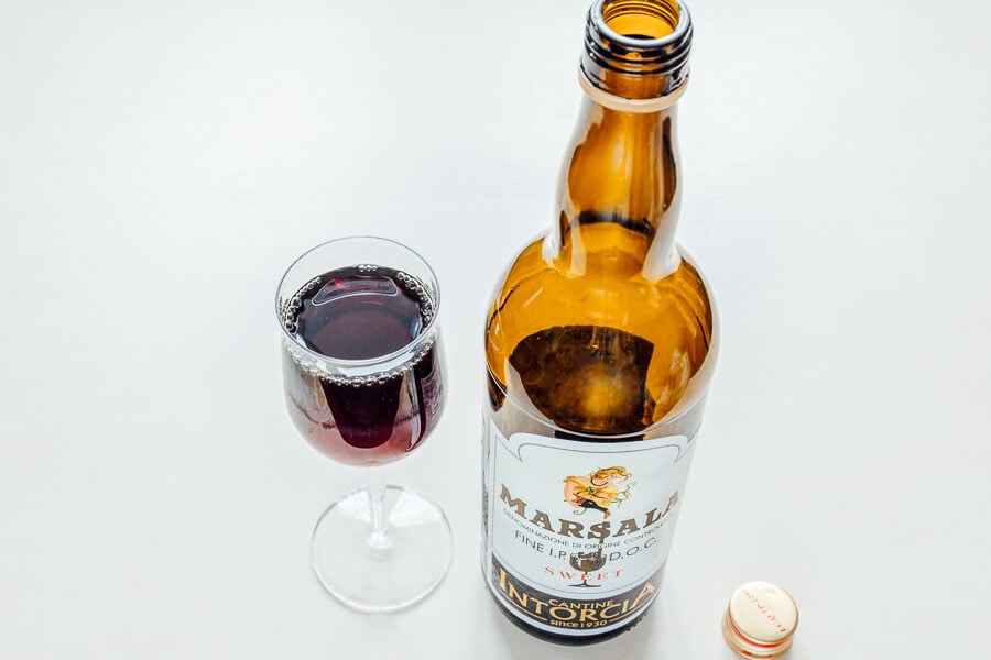 An open bottle of Marsala wine on a white counter.
