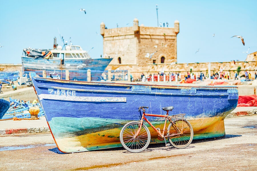A blue fishing boat and a bicycle on the harbour in Essaouira.