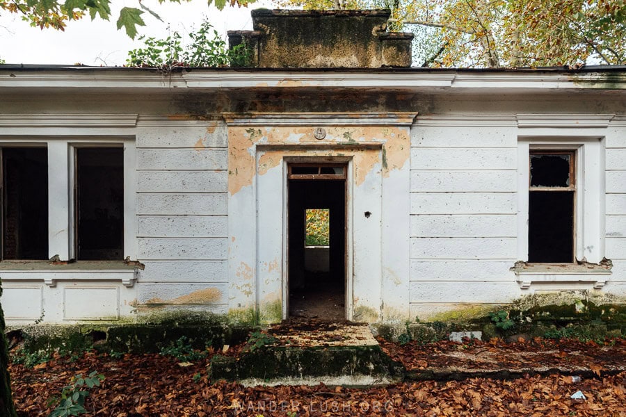 A dilapidated concrete building, formerly a summer dacha, surrounded by fallen leaves in autumn in Tskaltubo.