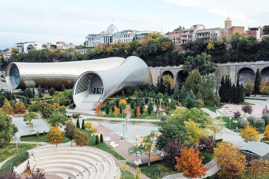 Two silver jug-shaped modern buildings inside Rike Park in autumn with colourful trees all around.