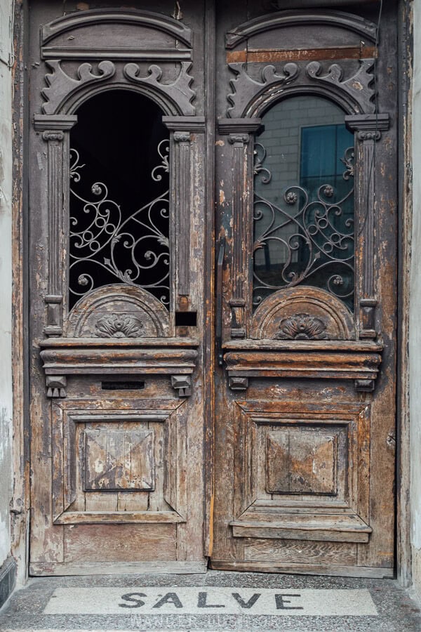 An old wooden door in Tbilisi, with the word Salve printed on the threshold.