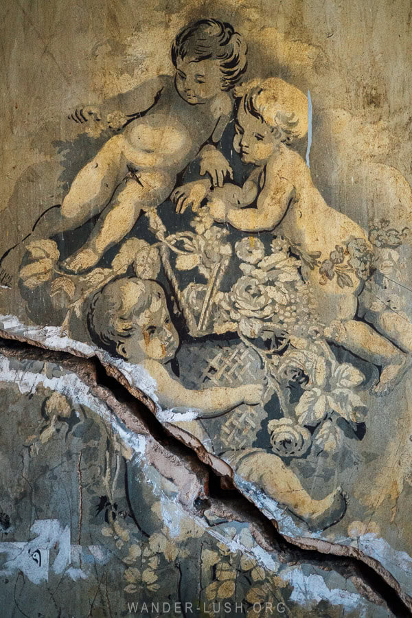A mural of three cherubs with a crack running through it on a wall in Old Tbilisi.