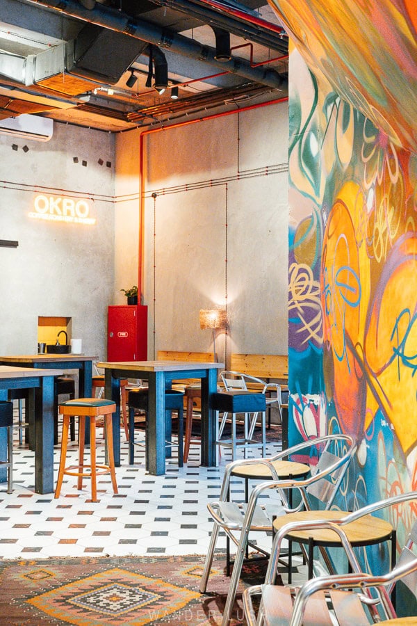 The interior of OKRO Roastery, a contemporary cafe in Tbilisi with cement walls and graffiti decorations.