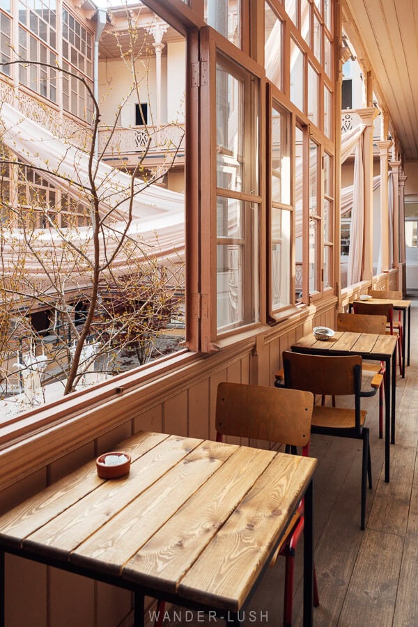 A beautiful veranda on a house in Old Tbilisi, with cafe seating next to the windows.