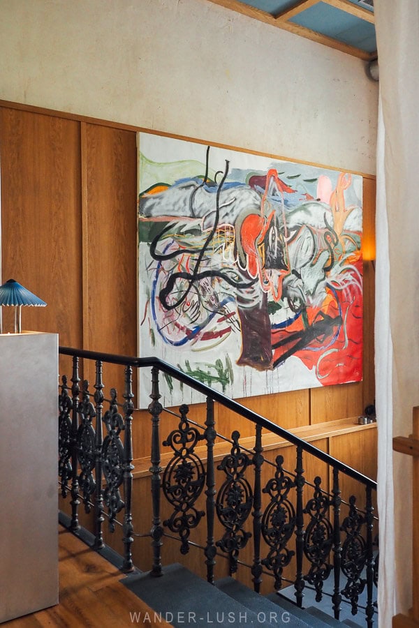 The entryway to a beautiful boutique hotel and cafe in Tbilisi, with an iron staircase and dramatic artwork.