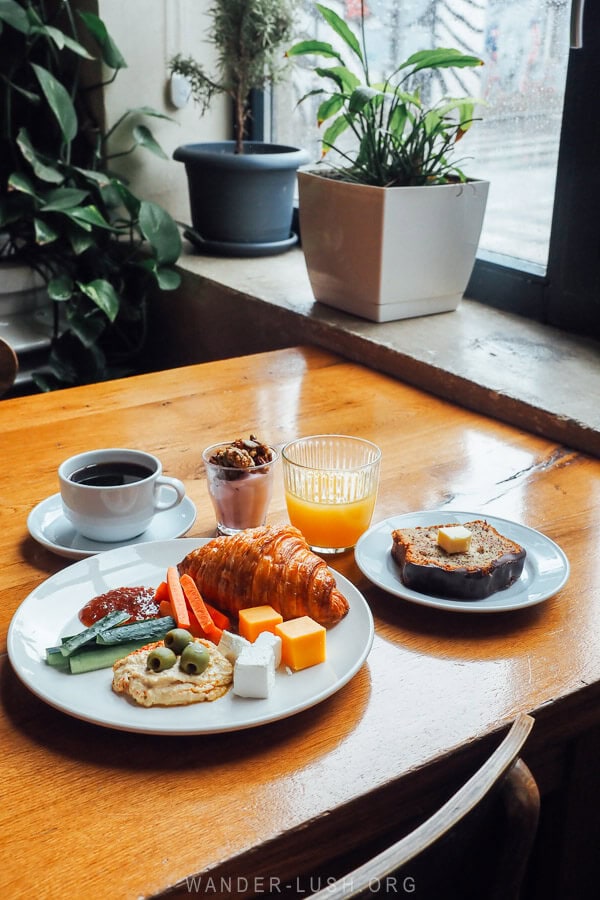 A breakfast spread at the Fabrika buffet in Tbilisi, featuring a plate of hummus, banana bread, and various drinks.