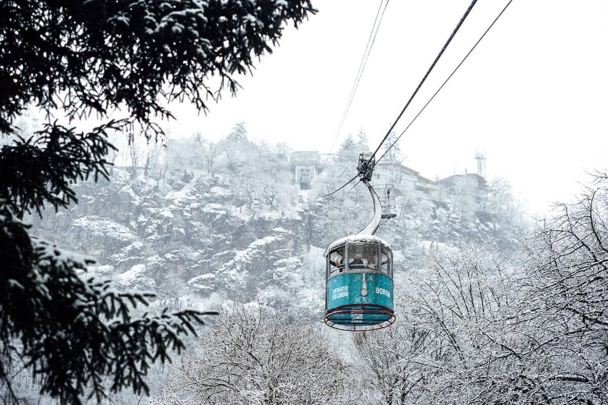 The Borjomi Cable Car in winter, a aqua gondola sailing over snow covered trees in the Borjomi Valley in Georgia.