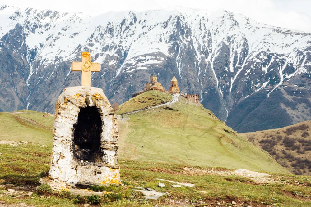 A church sits against a backdrop of snow-capped mountains in Kazbegi, Georgia.