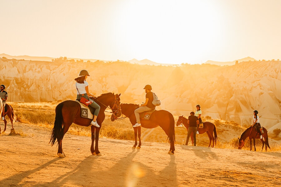Tourists riding horses in the sunset in Cappadocia, Turkey.
