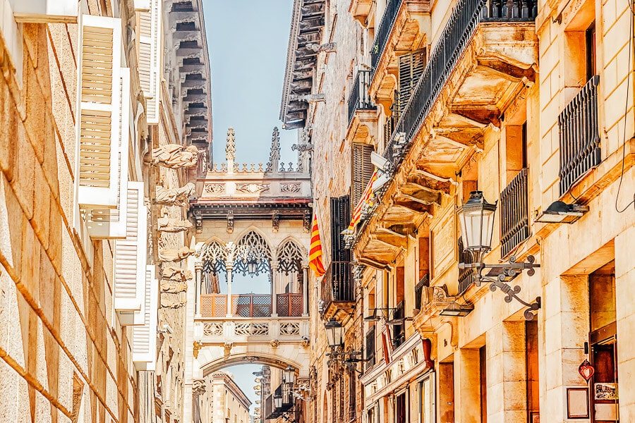 Beautiful architecture and a covered bridge lit up by sunshine in Barcelona's Gothic Quarter.