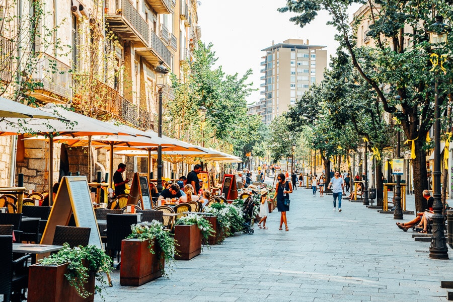 Pedestrians wander past sidewalk cafes on La Rambla, a famous walking street in Barcelona.