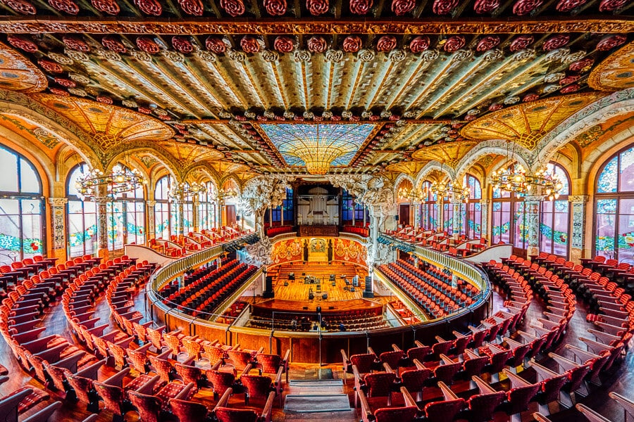 A wide shot of the Palau de la Musica Catalana, a concert hall in Barcelona with stained glass and opulent decorations.