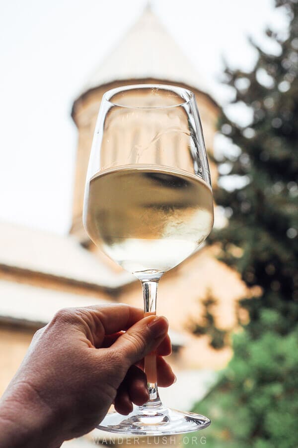 Holding a glass of white wine out in front of Sioni Cathedral in Tbilisi.