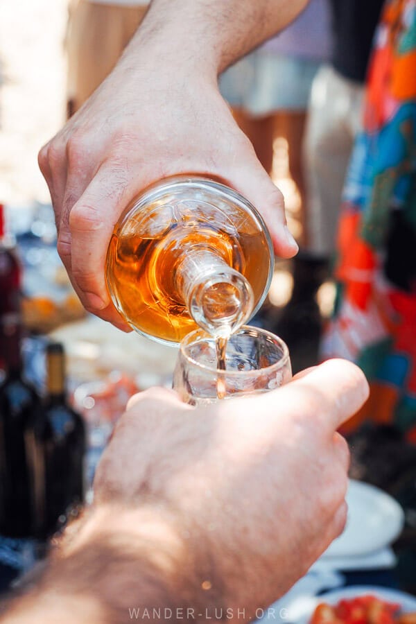 A man pours amber-coloured, oak-aged chacha liquor into a glass.