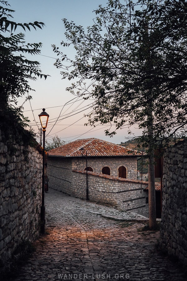 An old house at sunset, lit by a lamppost inside Berat Castle.
