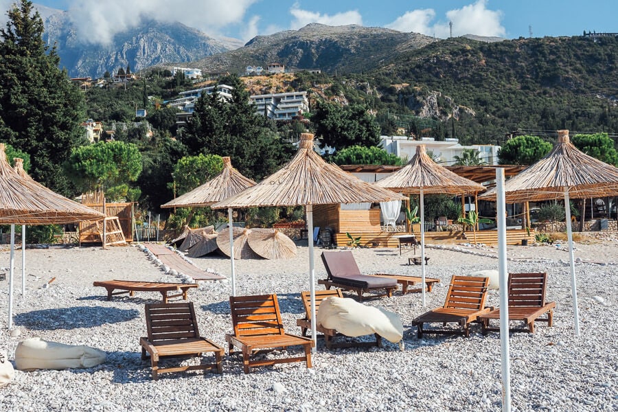 Beach chairs and thatched umbrellas set up on the beach in Dhermi, Albania.
