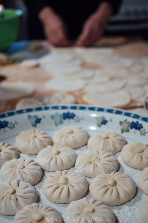 A woman makes khinkali dumplings and places them on a white plate in a home kitchen in Pankisi Valley, Georgia.