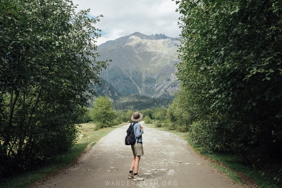 Emily dressed in hiking gear looking out towards the Greater Caucasus mountains from a hiking path in Mazeri, Svaneti.