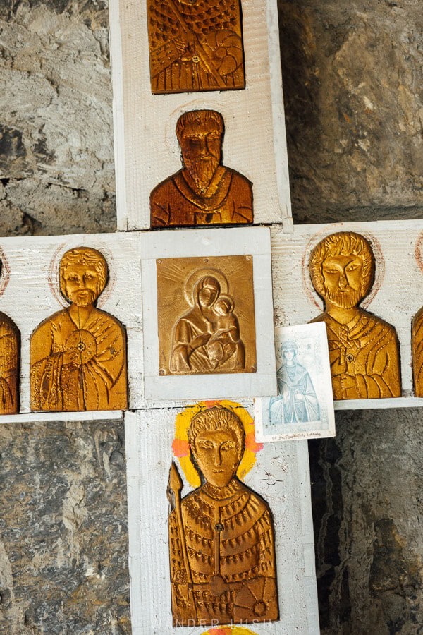 A cross with wooden carvings of saints inside a small makeshift chapel on the road from Mestia to Ushguli in Svaneti, Georgia.