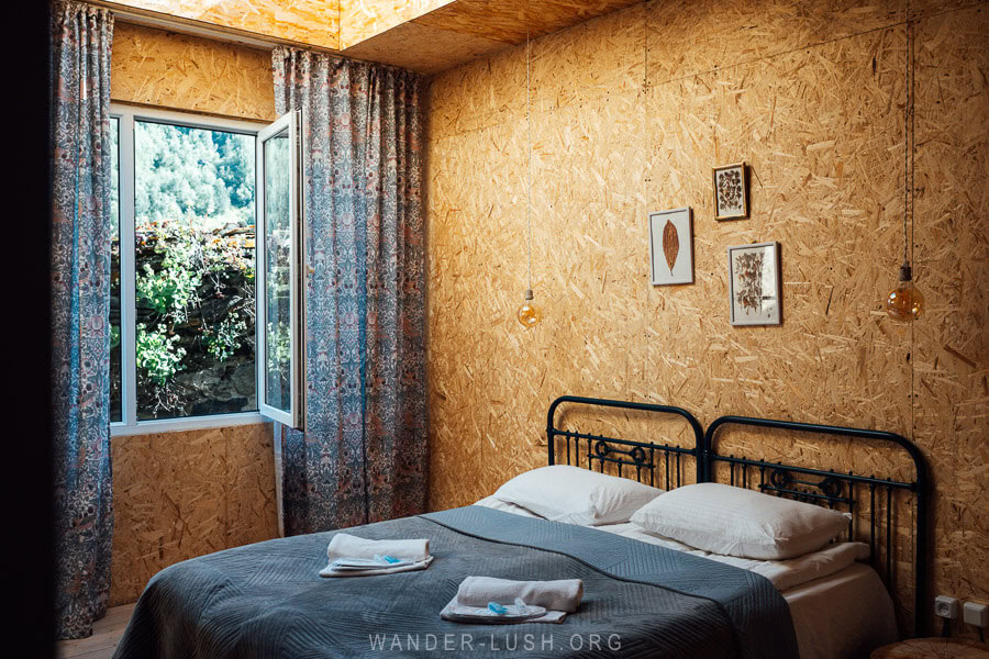 A modern guesthouse room with a double bed and a window looking out to a small village in Ushguli, Georgia.
