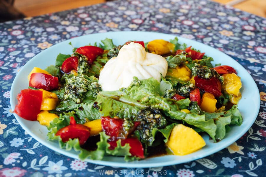 A vibrant salad with tomatoes, mango and pesto served on a colourful cafe table in Ushguli, Georgia.