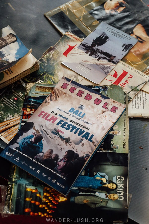 A stack of worn magazines and brochures featuring a schedule for the Dali IV & Svaneti International Film Festival 2021, with images of past film events.