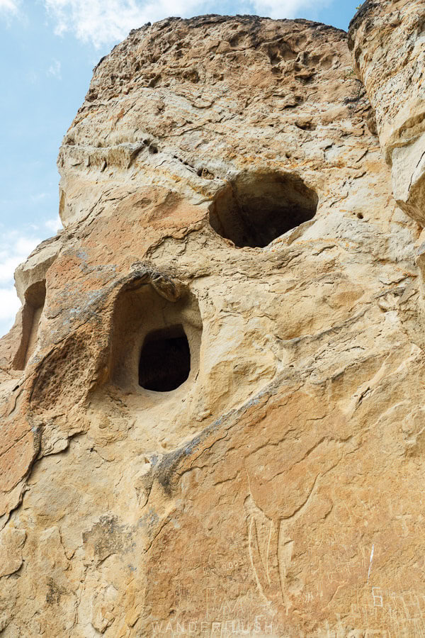 A tall rock wall with man-made holes cut its in face for burial tombs at an ancient archaeological site in Kaspi, Georgia.