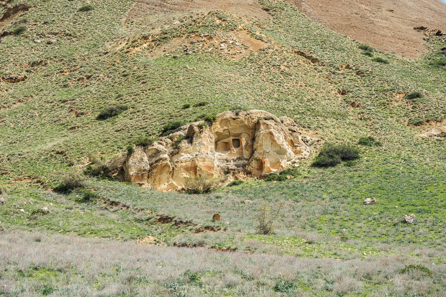 A low-lying rock face carved with burial chambers in the landscape outside Kaspi, Georgia.