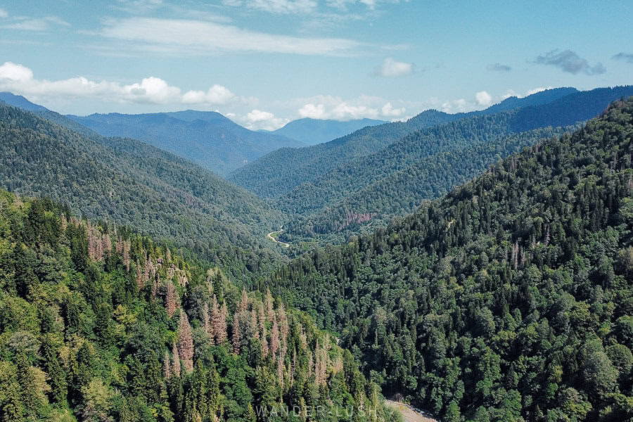 A panorama of mountains, with a winding road or river just visible in the valley against a blue sky in Georgia's Samtskhe-Javakheti region.