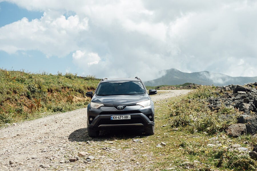 A grey 4WD on a rough stone road at the top of the Zekari Pass in Georgia.