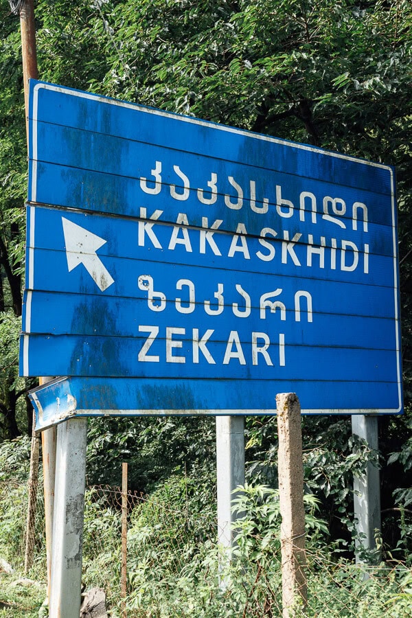 A blue road sign in English and Georgian points towards the new road from Baghdati to the Zekari Pass.