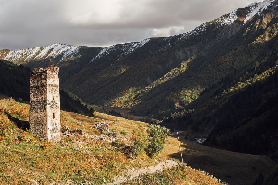 A Svan tower on a ridge outside the village of Khalde en route from Mestia to Ushguli, with a storm rolling in over golden leaves in autumn.