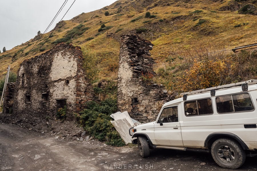 A white car parked on the side of dirt road in the village of Khalde in Svaneti.
