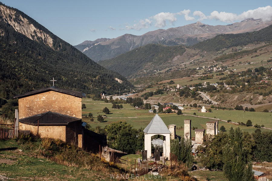 A village and stone church viewed from a hiking trail when trekking from Mestia to Ushguli in Svaneti, Georgia.