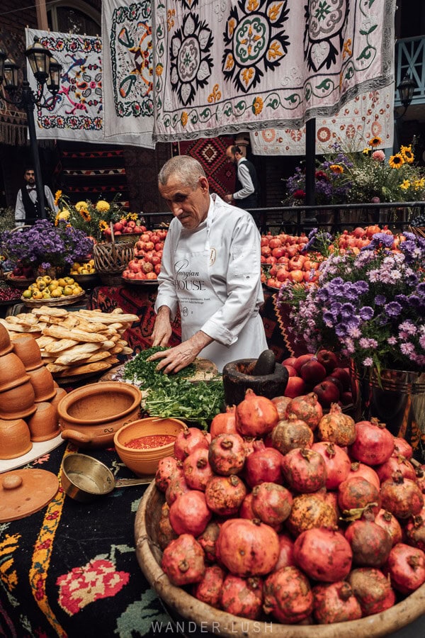 A chef chops a bundle of herbs for lobio amidst an arrangement of autumn produce at Georgian House restaurant during the Tbilisoba festival.