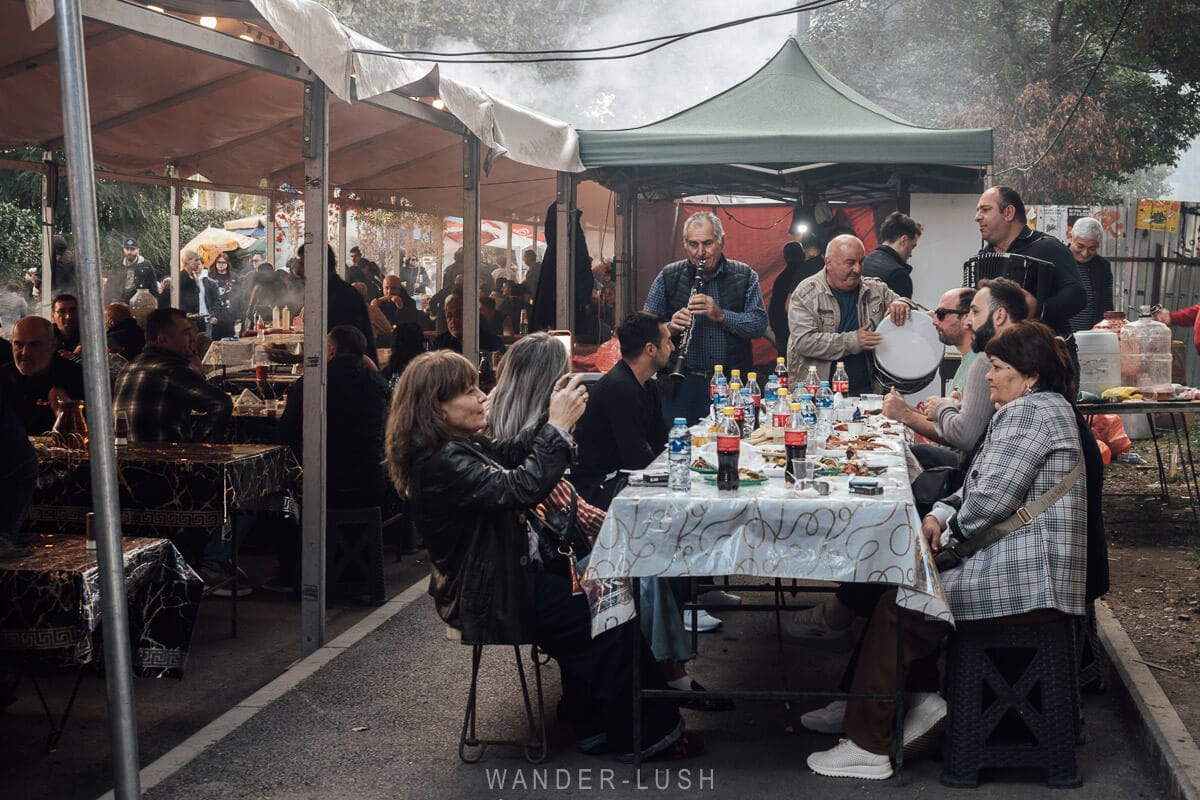 A family sits at a table while a three-piece band performs for them at a street festival during Tbilisoba in Tbilisi, Georgia.