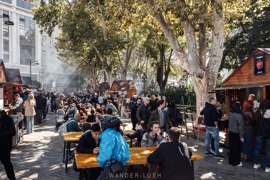 Familes seated at outdoor tables at a street food festival in Tbilisi during the Tbilisoba festival.