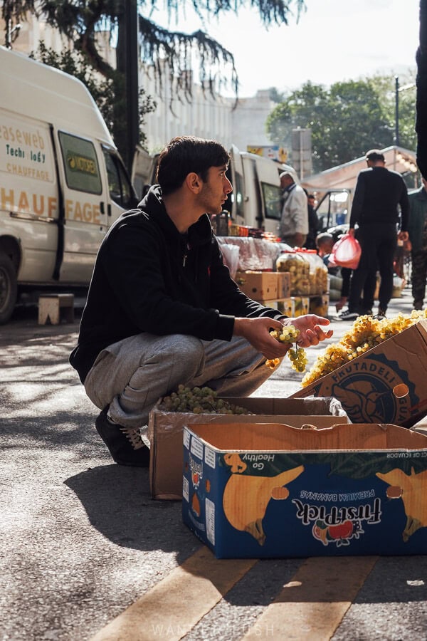 A man holds a bunch of grapes from a box at a street market in Tbilisi.