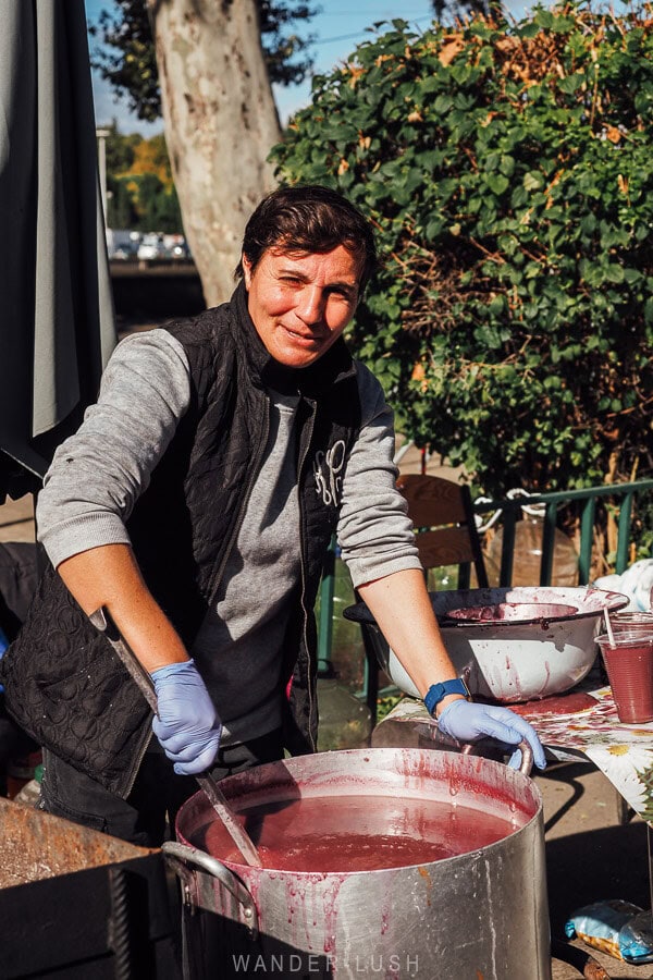A woman stirring a pot of pink pelamushi, a traditional Georgian dessert.