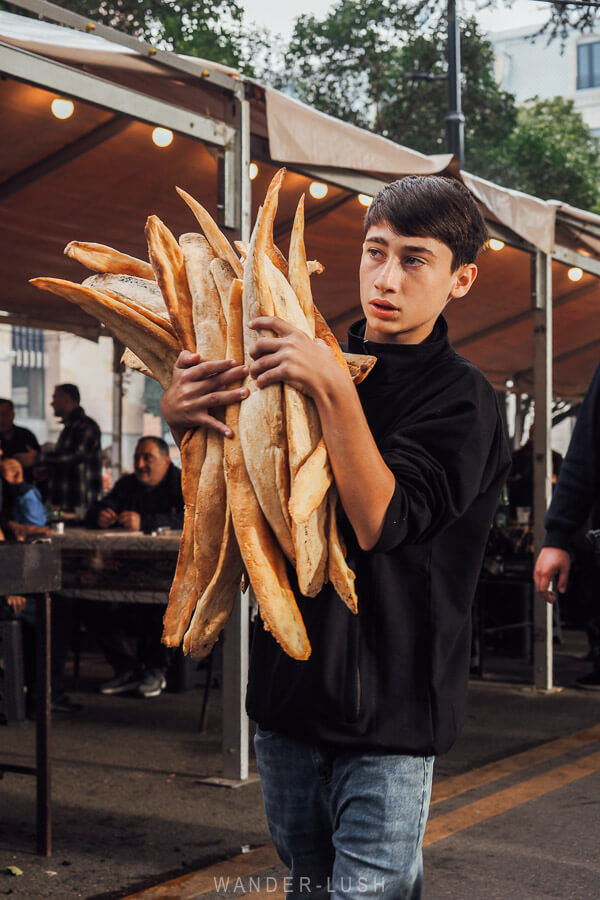 A young man carries an armful of Georgian shoti bread at a street festival in Tbilisi.